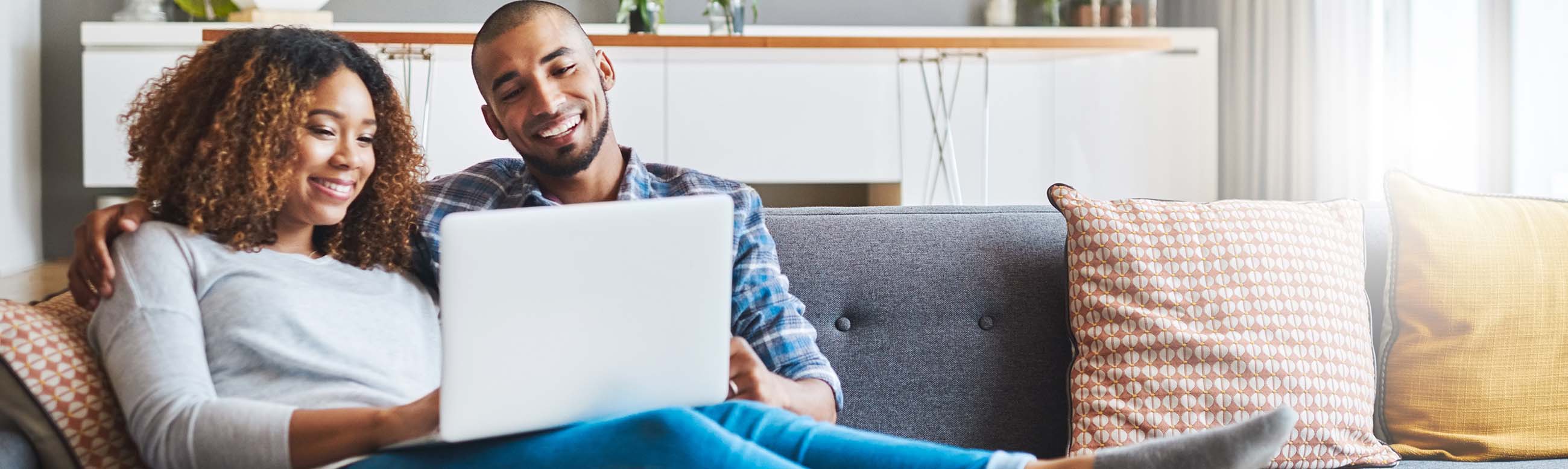 a couple looking at a laptop while sitting on the couch